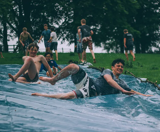 Teenagers jumping into a lake at sunset