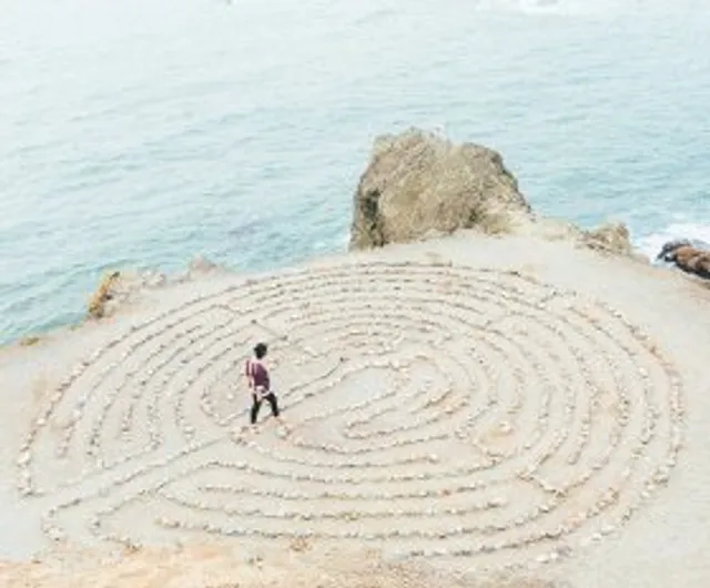A person walking a stone labyrinth on a beach