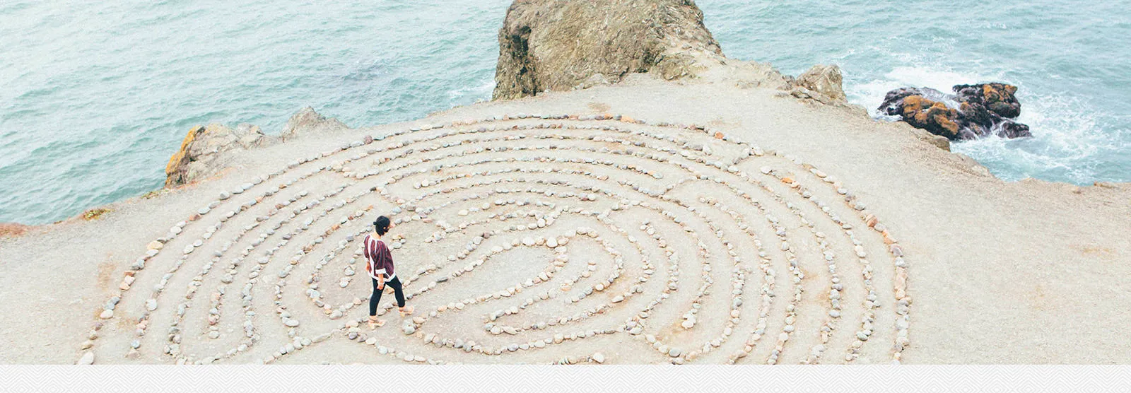 A person walking a large stone labyrinth on a beach